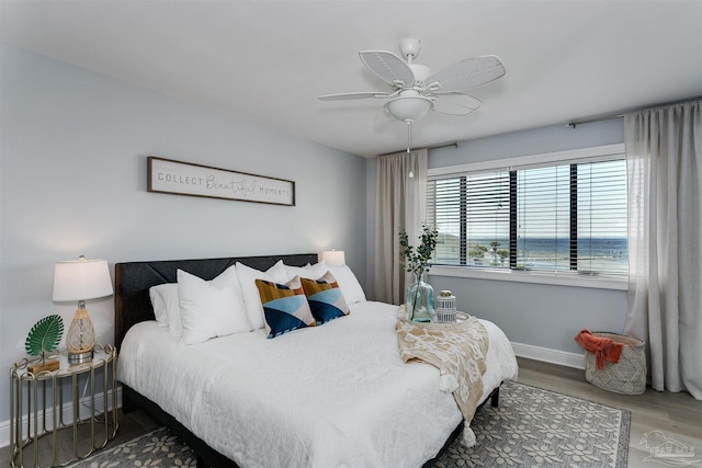 bedroom featuring ceiling fan, hardwood / wood-style flooring, and a water view