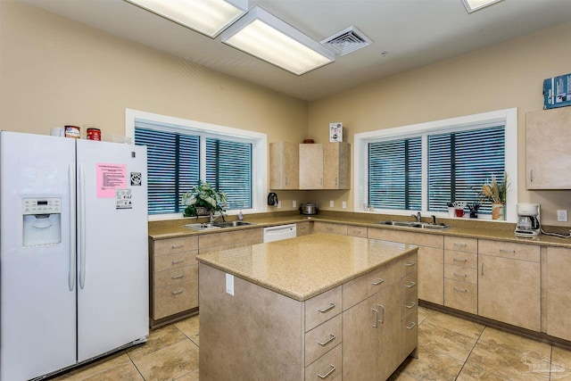 kitchen featuring light brown cabinetry, sink, white appliances, and a kitchen island