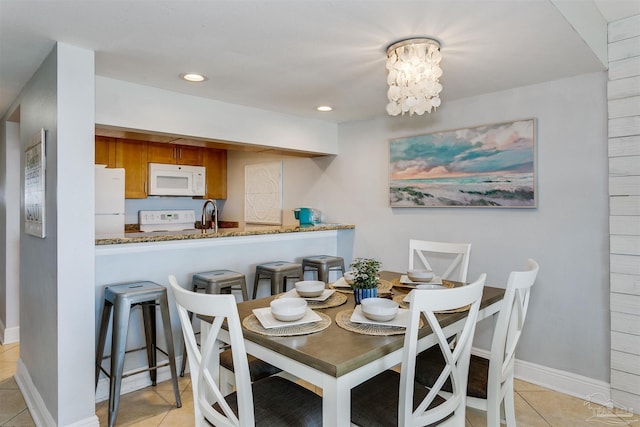 dining area featuring sink, light tile patterned flooring, and an inviting chandelier