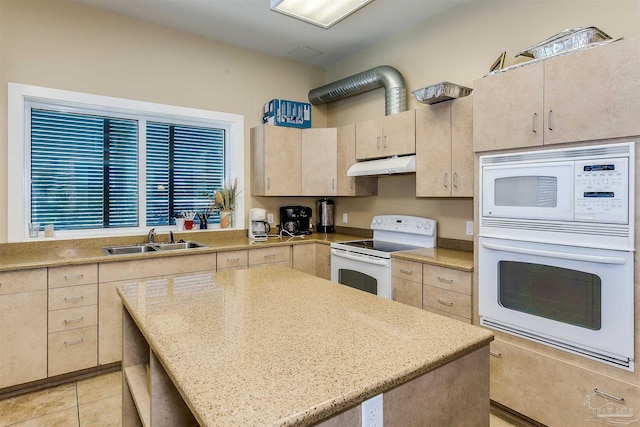 kitchen featuring a center island, sink, white appliances, light stone countertops, and light brown cabinetry