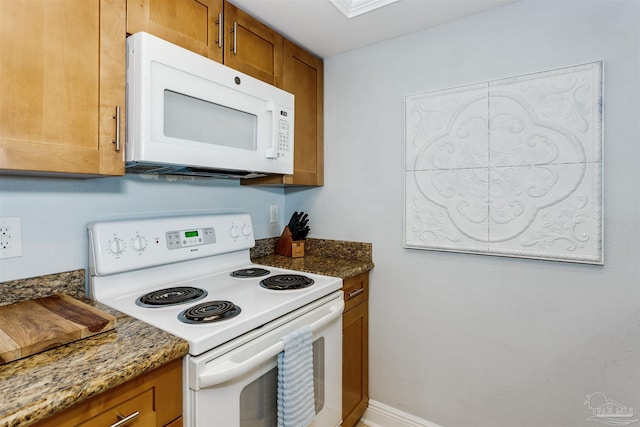 kitchen featuring dark stone countertops and white appliances