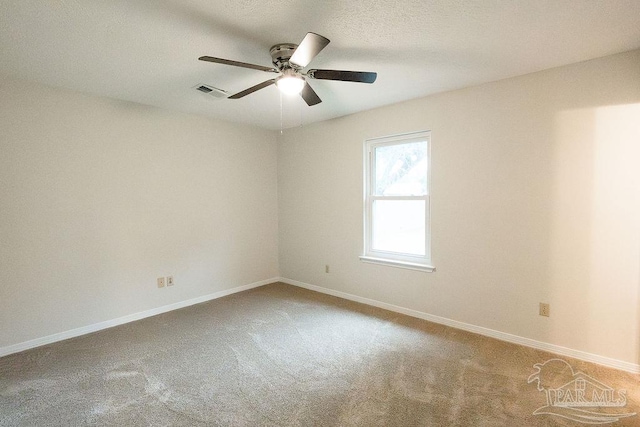 carpeted spare room featuring a ceiling fan, visible vents, and baseboards