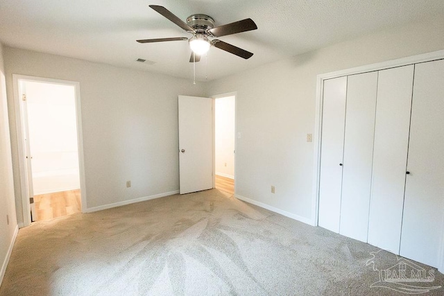 unfurnished bedroom featuring baseboards, ensuite bath, visible vents, and light colored carpet