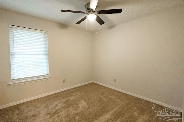 carpeted spare room featuring a ceiling fan and baseboards