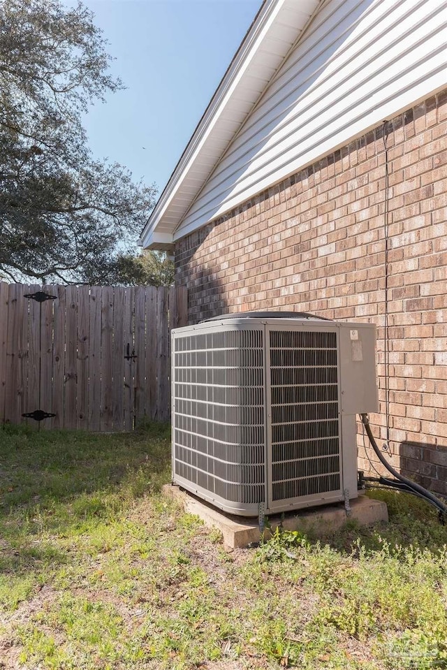 exterior details with fence, central AC, and brick siding