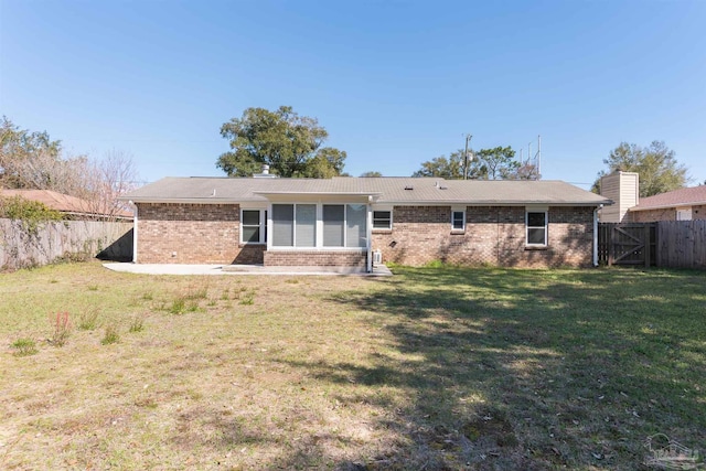 back of house with a fenced backyard, a lawn, and brick siding