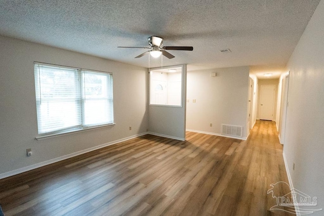 empty room featuring baseboards, ceiling fan, visible vents, and wood finished floors