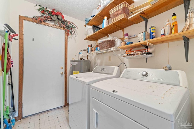 laundry area with a textured ceiling, electric water heater, and washing machine and dryer