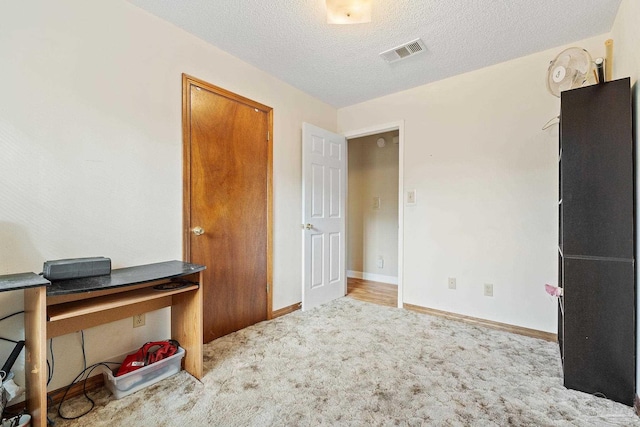 carpeted office featuring a textured ceiling