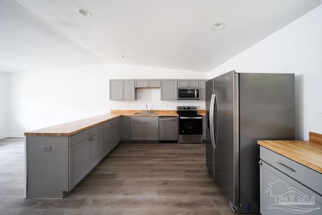 kitchen with dark hardwood / wood-style floors, sink, vaulted ceiling, appliances with stainless steel finishes, and gray cabinets