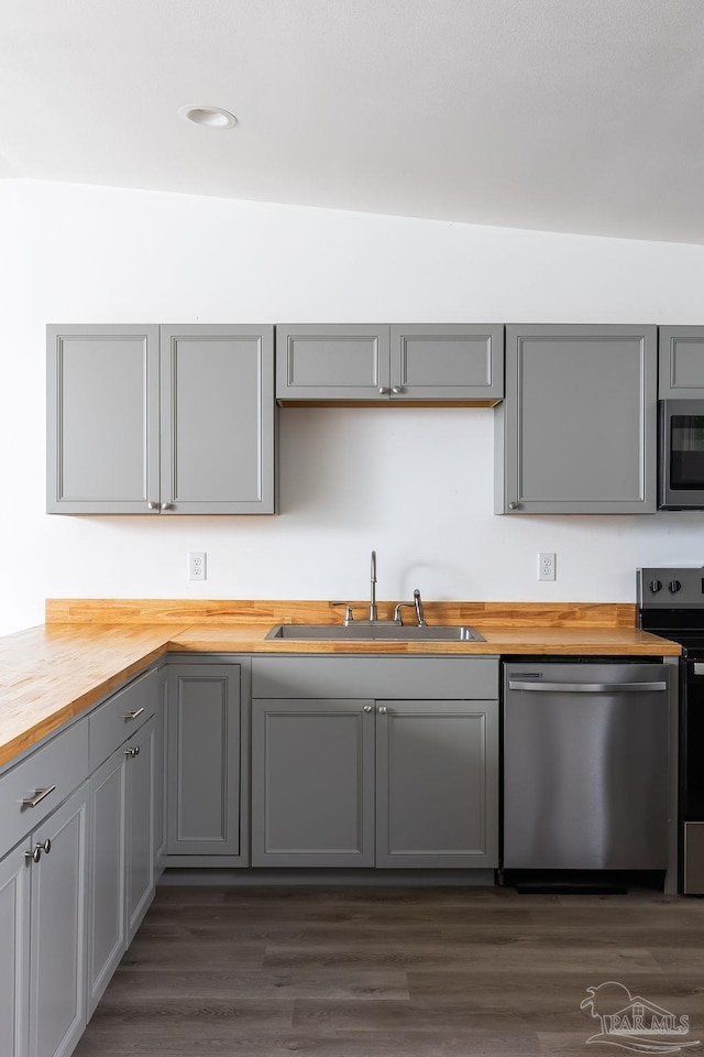 kitchen with butcher block countertops, appliances with stainless steel finishes, sink, and gray cabinetry