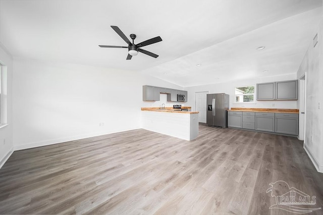 unfurnished living room with wood-type flooring, sink, vaulted ceiling, and ceiling fan