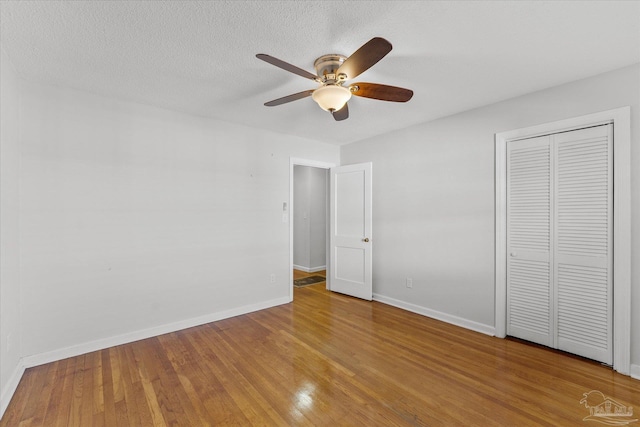 unfurnished bedroom featuring hardwood / wood-style floors, a textured ceiling, ceiling fan, and a closet