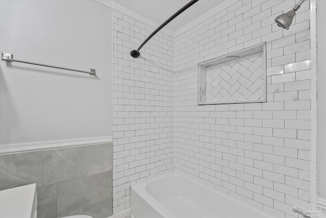 bathroom featuring tiled shower / bath combo, tile walls, and toilet