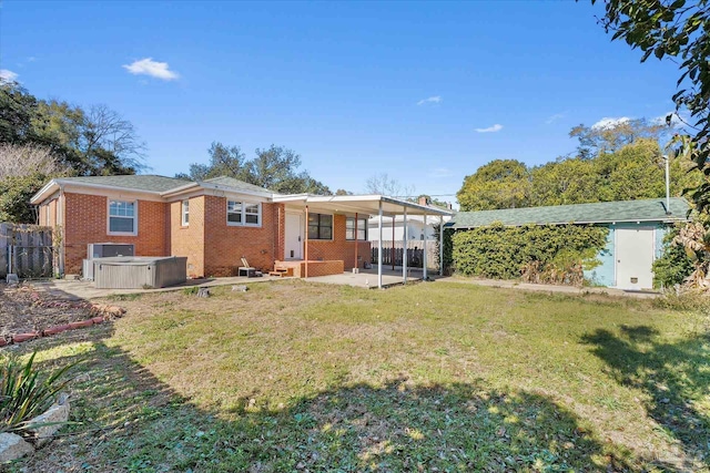 rear view of property with a hot tub, a patio area, and a lawn