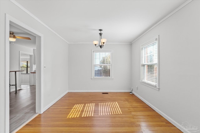 unfurnished dining area featuring crown molding, ceiling fan with notable chandelier, and hardwood / wood-style floors