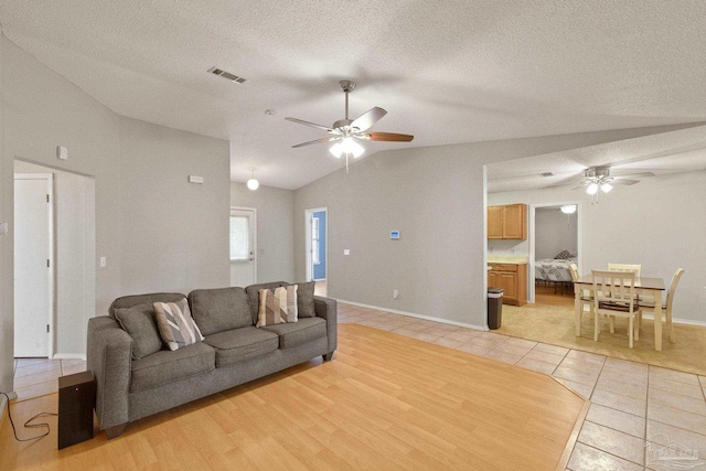 living room featuring a textured ceiling, ceiling fan, light hardwood / wood-style floors, and lofted ceiling