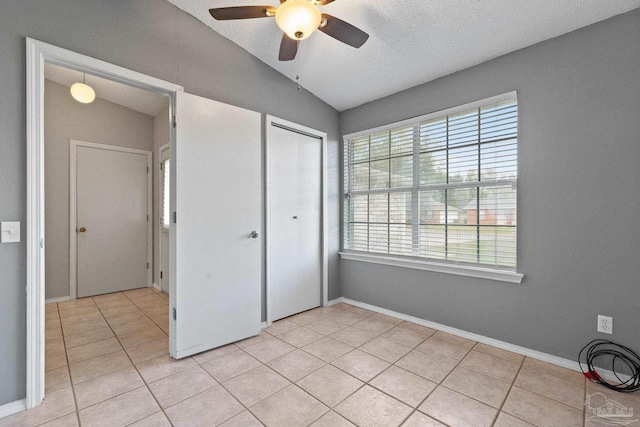 unfurnished bedroom with ceiling fan, a closet, light tile patterned floors, and lofted ceiling