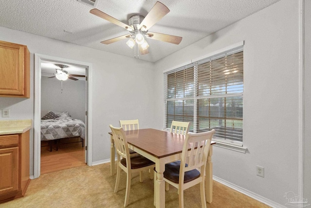 carpeted dining space with ceiling fan and a textured ceiling