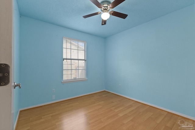 spare room featuring ceiling fan, light wood-type flooring, and a textured ceiling