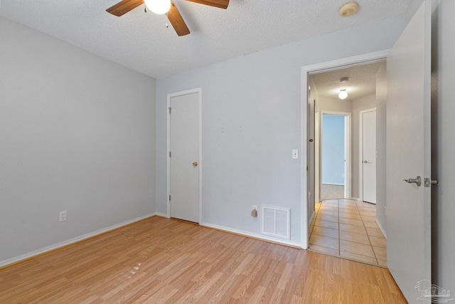 spare room with ceiling fan, light hardwood / wood-style flooring, and a textured ceiling