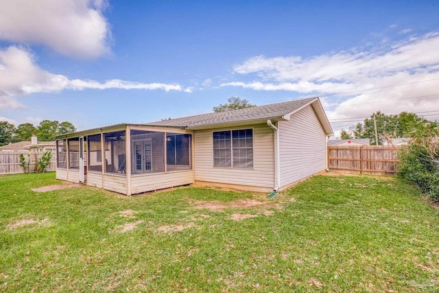 rear view of house featuring a sunroom and a yard