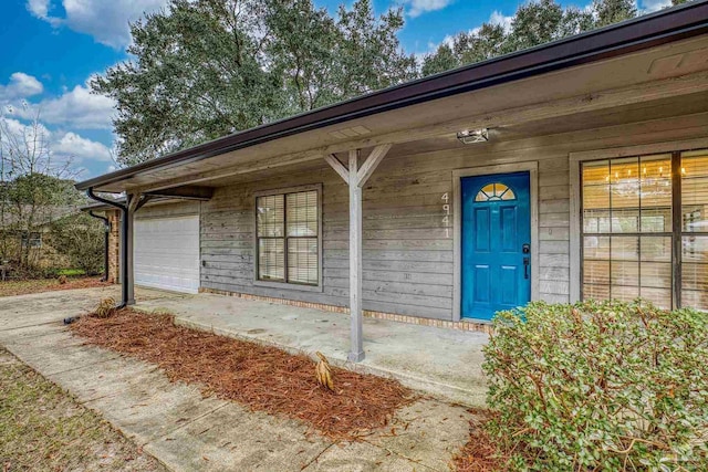 entrance to property featuring a porch and a garage