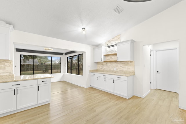 kitchen with white cabinetry, light hardwood / wood-style flooring, and lofted ceiling