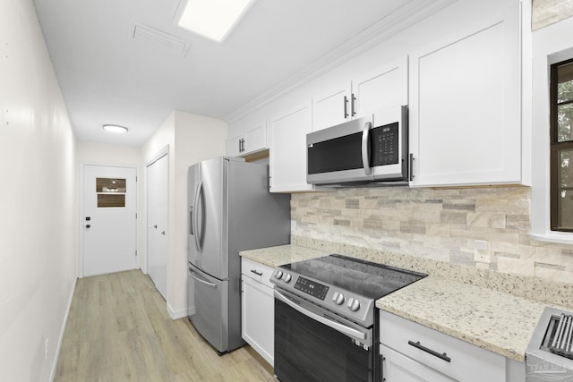 kitchen with light hardwood / wood-style flooring, stainless steel appliances, light stone countertops, white cabinets, and decorative backsplash