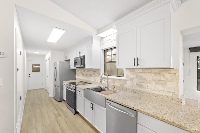 kitchen with white cabinetry, sink, light stone counters, and stainless steel appliances