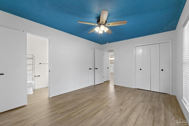 unfurnished bedroom featuring ceiling fan, connected bathroom, a textured ceiling, and light wood-type flooring