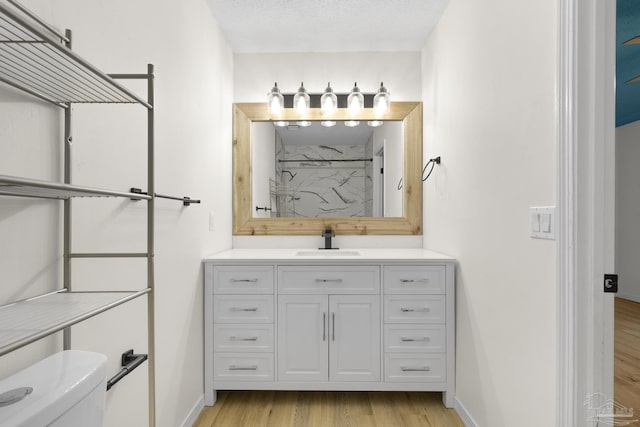 bathroom with hardwood / wood-style floors, a shower, vanity, toilet, and a textured ceiling