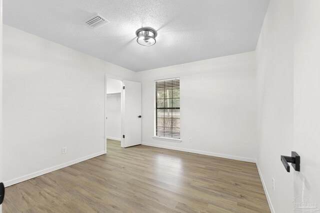 spare room featuring light hardwood / wood-style floors and a textured ceiling