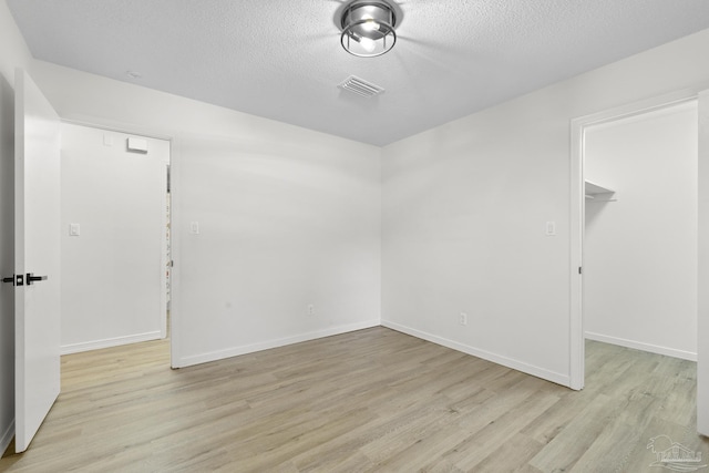 spare room with light hardwood / wood-style flooring and a textured ceiling