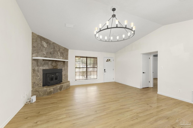 unfurnished living room with high vaulted ceiling, a fireplace, an inviting chandelier, and light hardwood / wood-style flooring