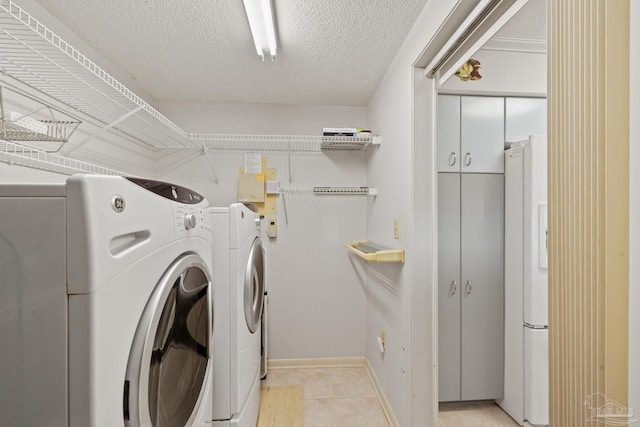 laundry room featuring separate washer and dryer, a textured ceiling, and light tile patterned floors