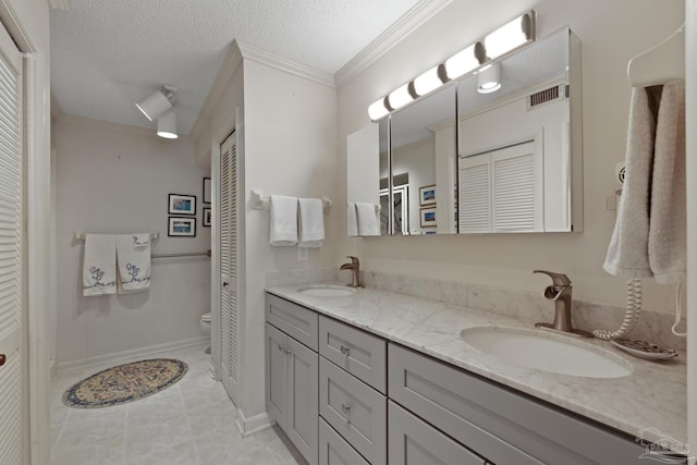 bathroom featuring vanity, a textured ceiling, crown molding, tile patterned flooring, and toilet