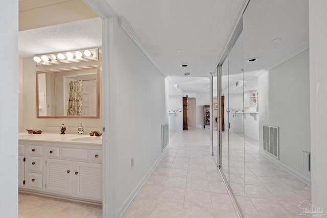 hall featuring light tile patterned flooring, sink, ornamental molding, and a textured ceiling