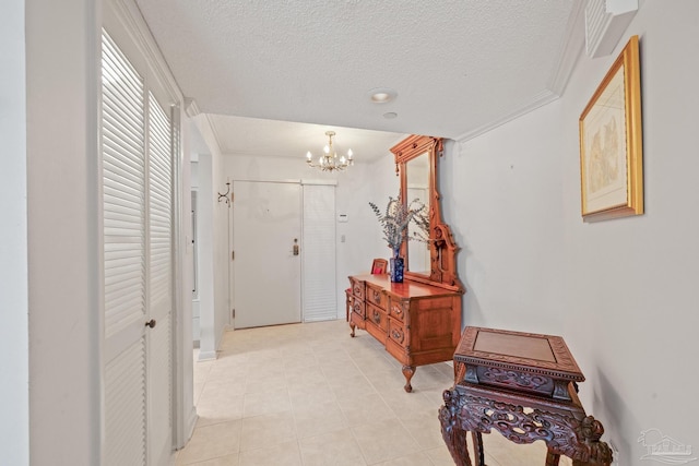 hallway featuring a chandelier, a textured ceiling, ornamental molding, and light tile patterned flooring