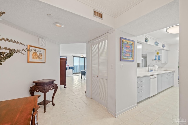 corridor featuring crown molding, sink, light tile patterned flooring, and a textured ceiling