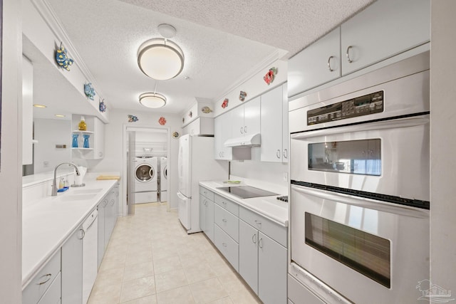 kitchen with white cabinetry, sink, stainless steel double oven, black electric stovetop, and washer and dryer