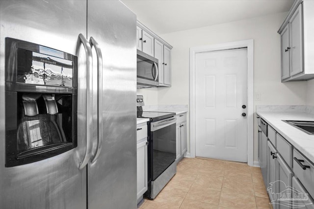 kitchen with appliances with stainless steel finishes, gray cabinets, light countertops, and light tile patterned floors