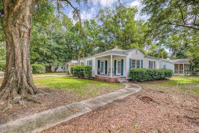 7074 Milton Ct, Milton, FL 32583 - view of front of home featuring a porch, a chimney, a front lawn, and a sunroom