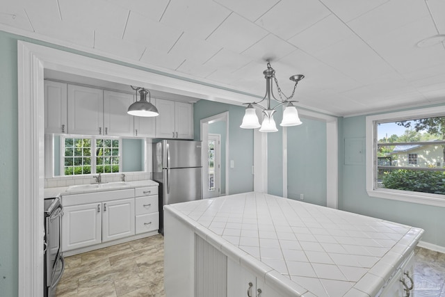 7074 Milton Ct, Milton, FL 32583 - kitchen featuring tile countertops, a sink, appliances with stainless steel finishes, pendant lighting, and white cabinets