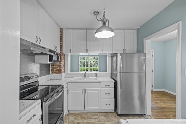 7074 Milton Ct, Milton, FL 32583 - kitchen with stainless steel appliances, tile counters, a sink, under cabinet range hood, and white cabinetry