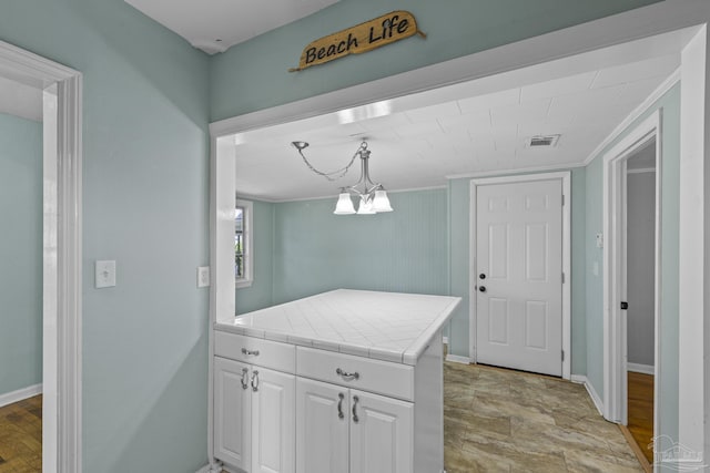 7074 Milton Ct, Milton, FL 32583 - kitchen with tile counters, white cabinets, hanging light fixtures, and baseboards