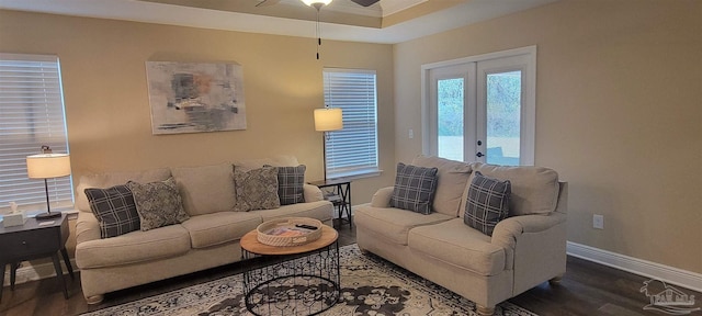 living room featuring a tray ceiling, crown molding, a ceiling fan, wood finished floors, and baseboards