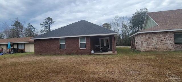 rear view of house with french doors, brick siding, roof with shingles, a lawn, and a patio area