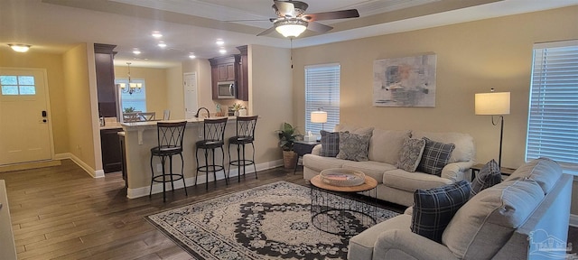 living area with dark wood-style floors, baseboards, and ceiling fan with notable chandelier