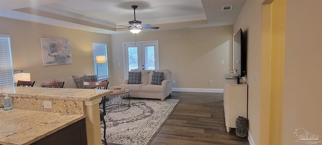 interior space with dark wood-style flooring, baseboards, french doors, a tray ceiling, and crown molding